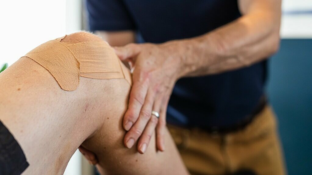 Practitioner assessing person's knee